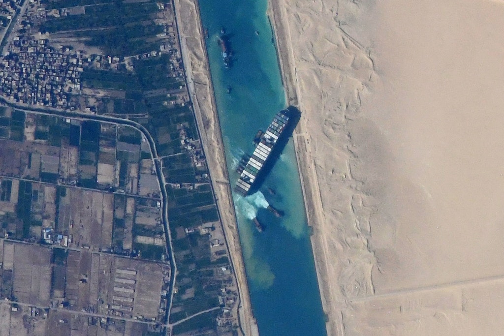 Bird's eye view of a large container ship stuck in a river.