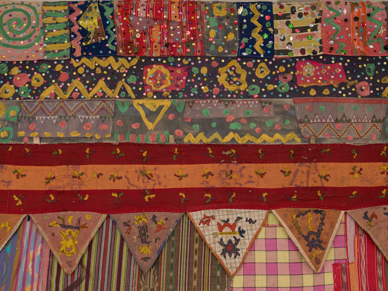 Close up image of an artwork made from a mixture of colorful fabircs and sewing techniques.