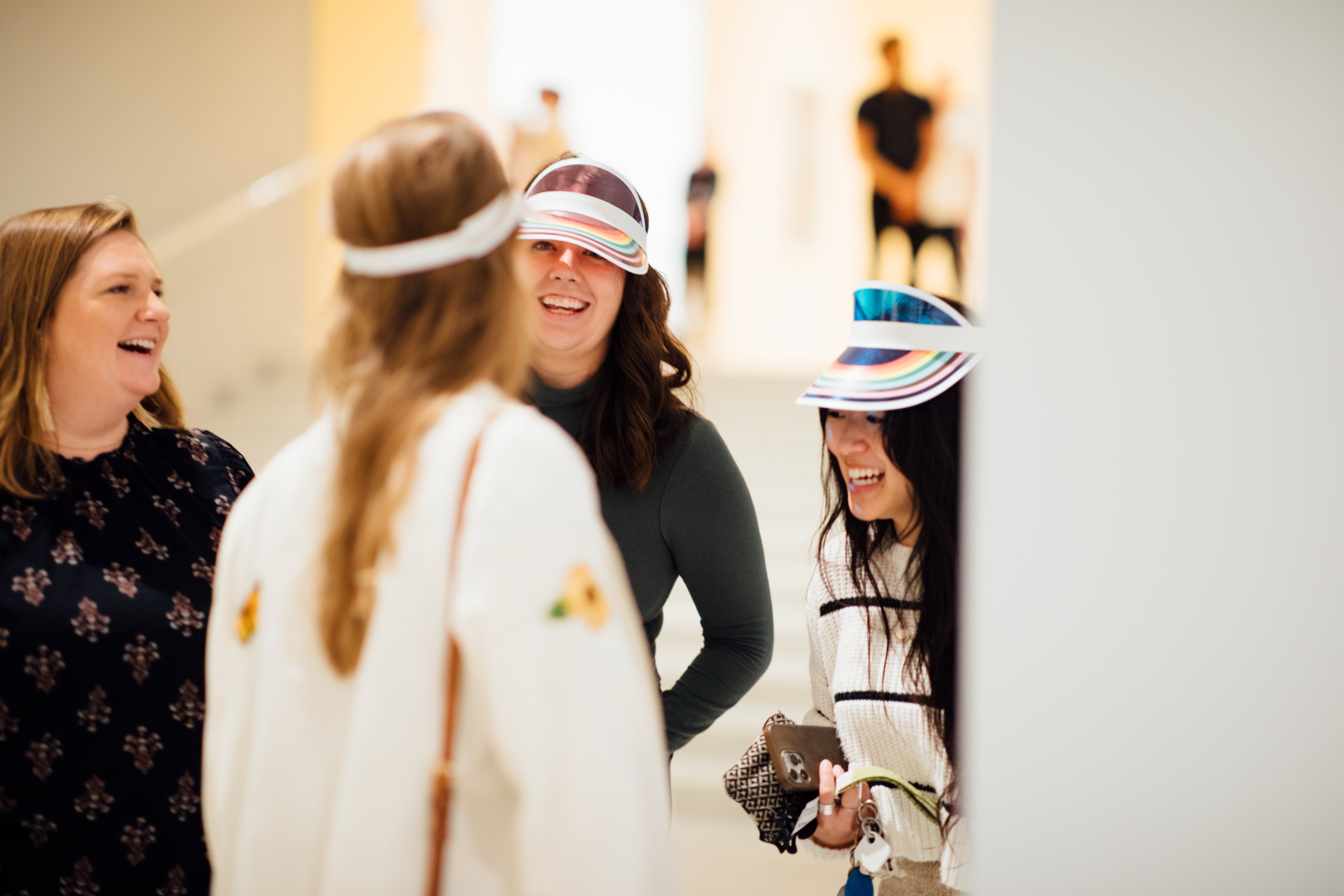 A group of four adults smiling and laughing in a gallery space.