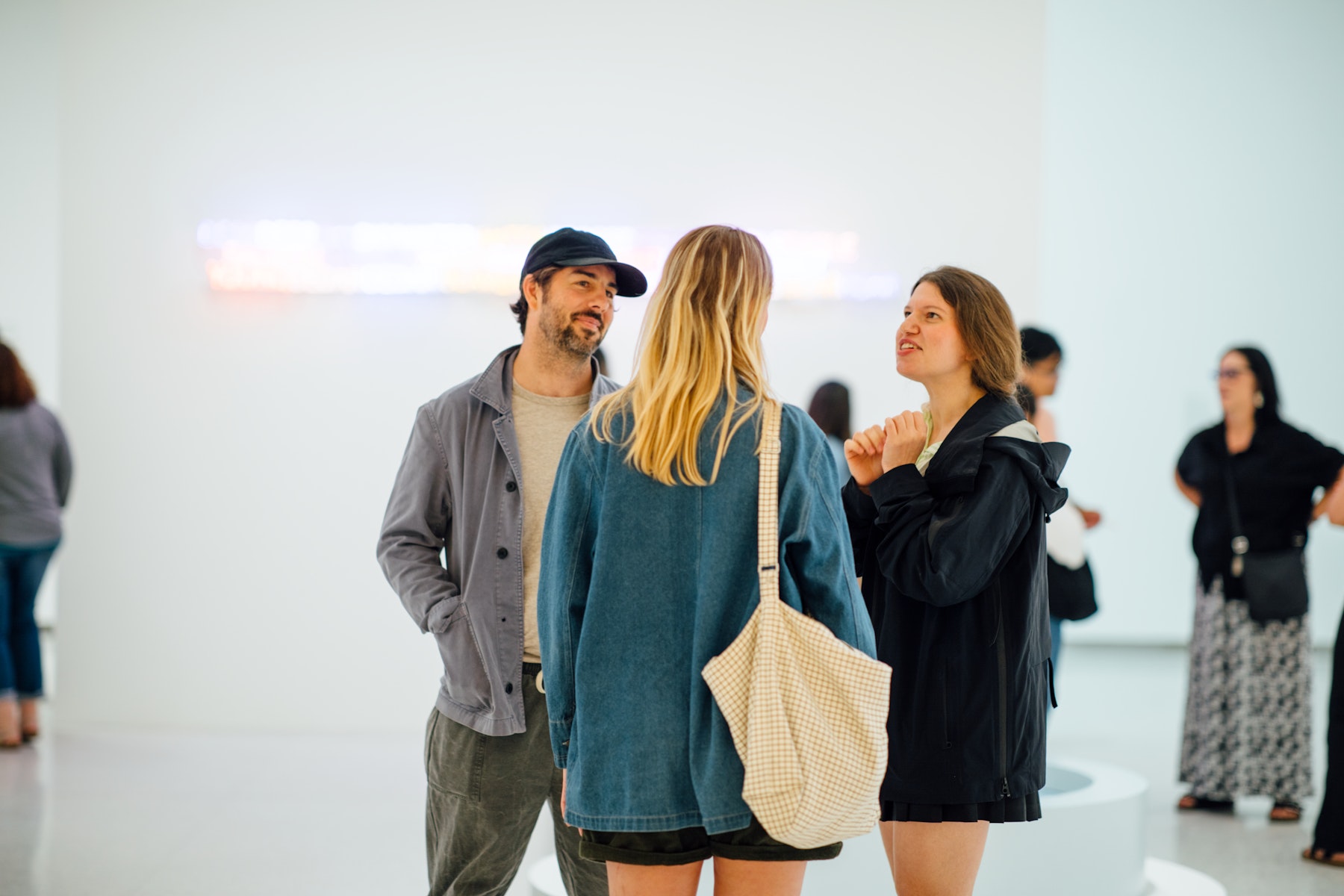 A group of people talking to eachother in a gallery.