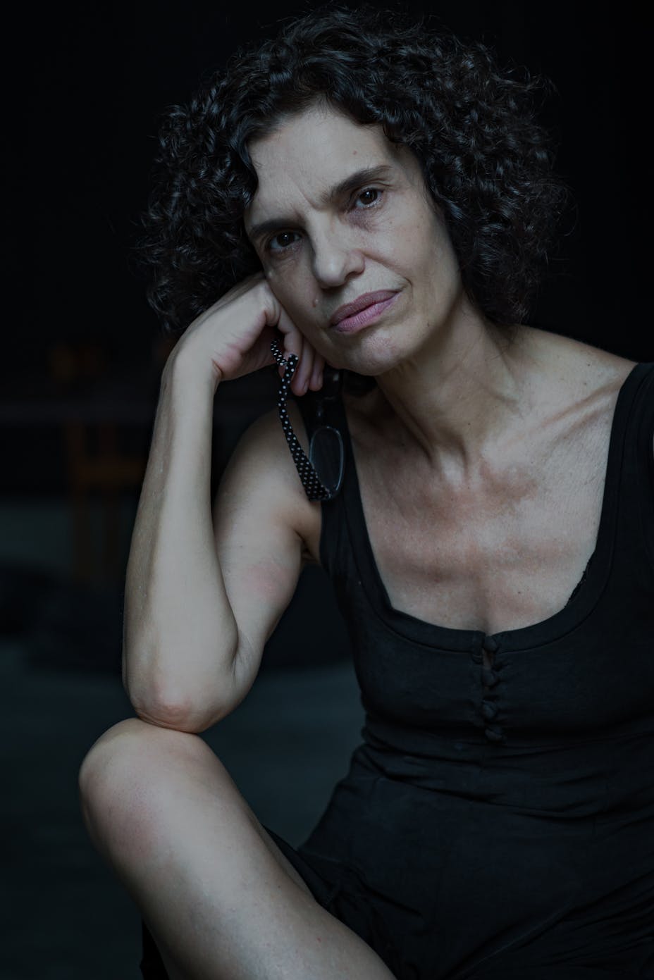 A woman sits and looks at the viewer.