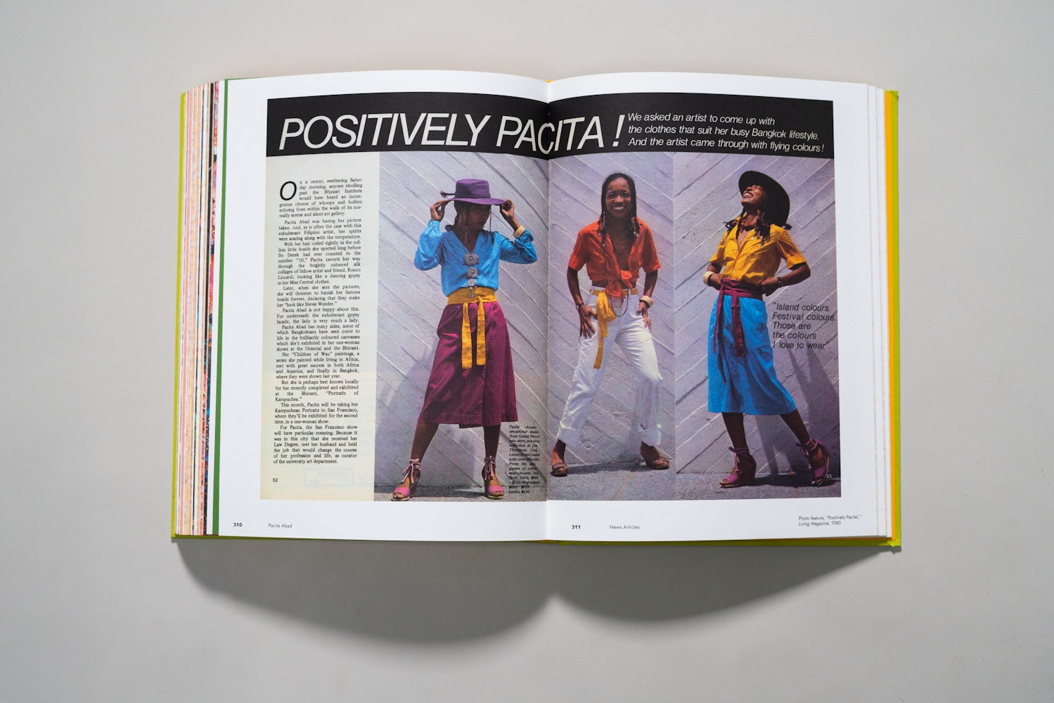 Spread of a large art book is open to a page of a photos of a woman modleing clothing with the title Positively Pacita!.