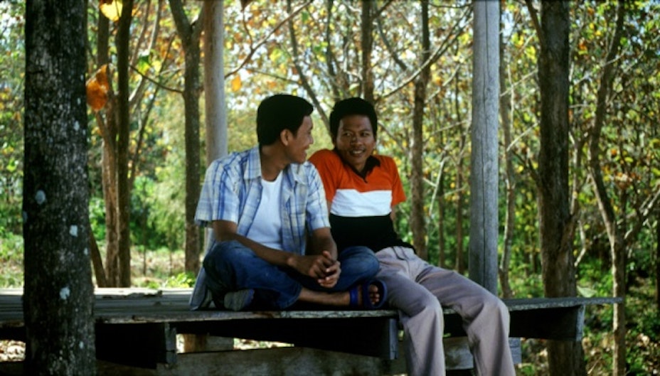 Two men sitting on a picnic table.