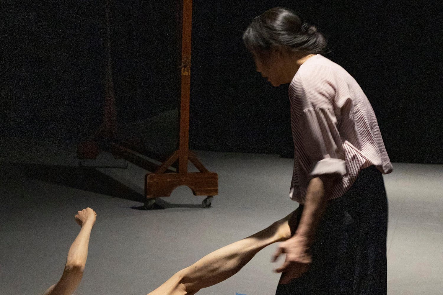 One performer with medium skin kicks another from the floor.