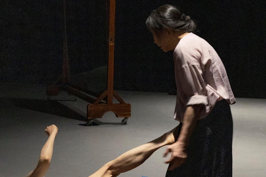 One performer with medium skin kicks another from the floor.