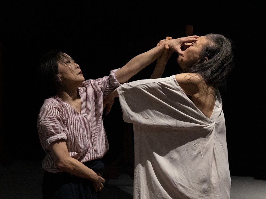 One performer with medium skin puts their hand on another's face.
