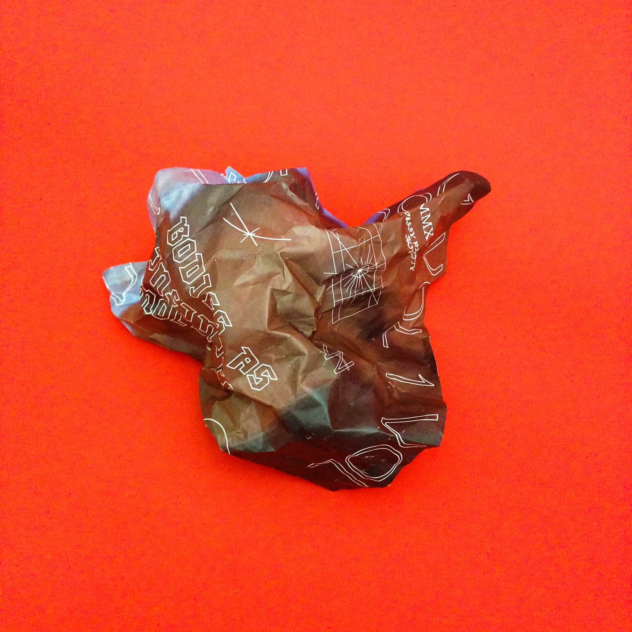 Image of crumpled paper with an organic shape with complex typography on red background