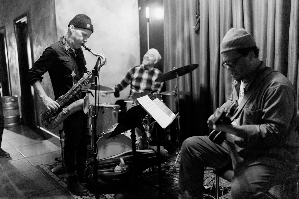 A three man jazz band plays together indoors.