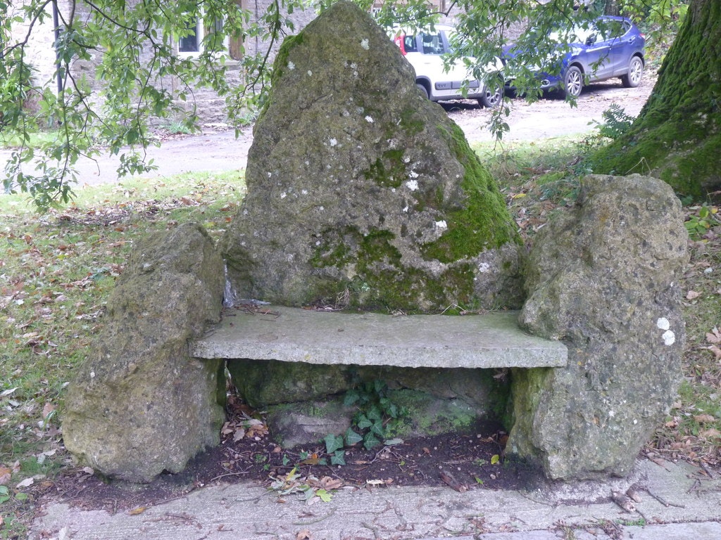 A concrete seat embeded in a rock with moss.
