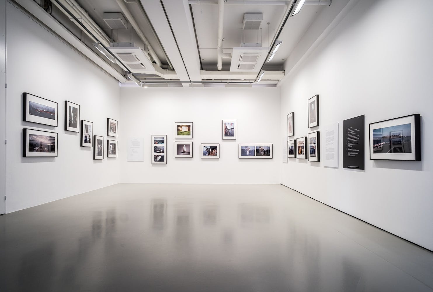 A series of photographs are hung salon style in a white art gallery.