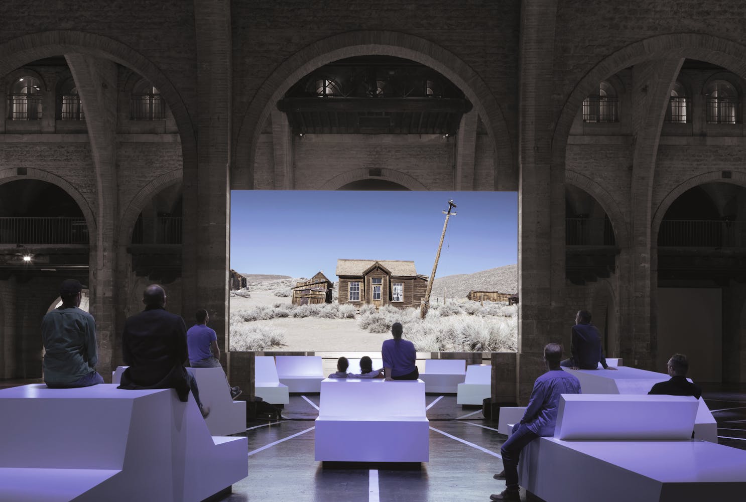 Image of film projected on screen with people sitting in chairs