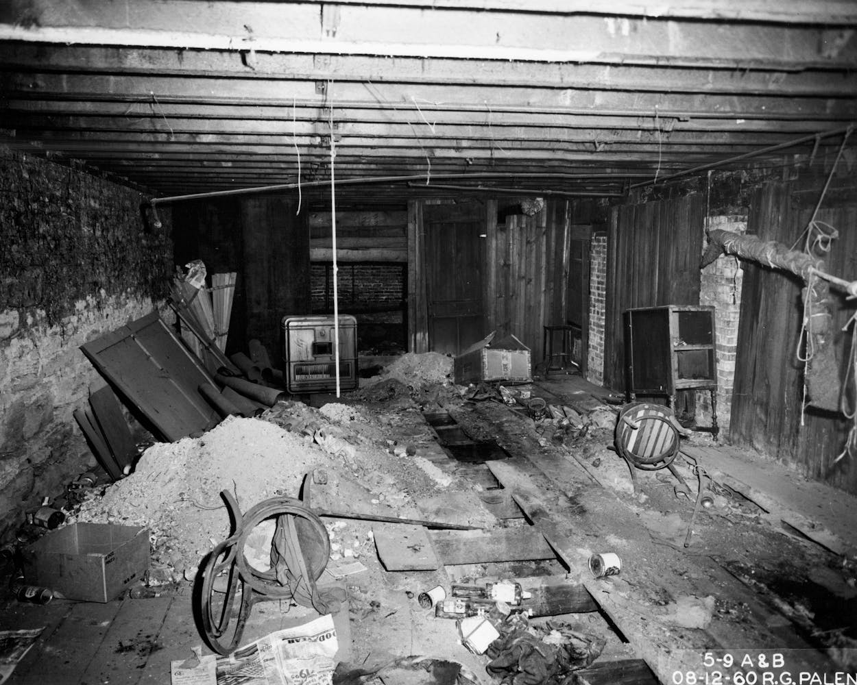 6. Archival image of the basement of the Pioneer Hotel. The floor is littered with trash, chairs and empty liquor bottles.