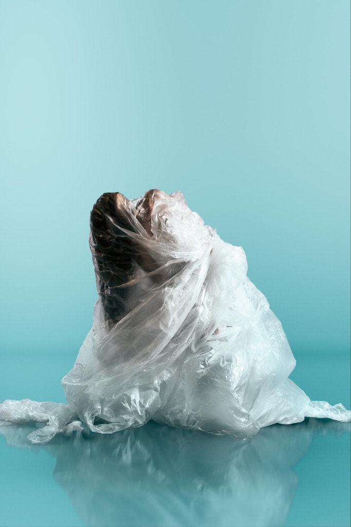 A white sculpted high heel sits atop layered, cake-like steps with a ribbon and flowing fabric at the base.