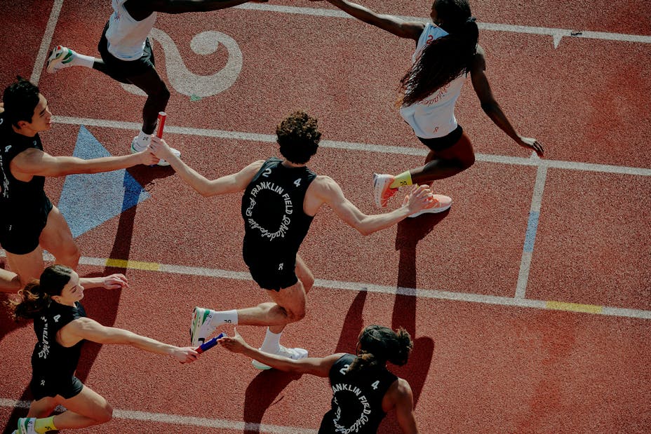 A birds-eye view of runners crossing a line on a running track