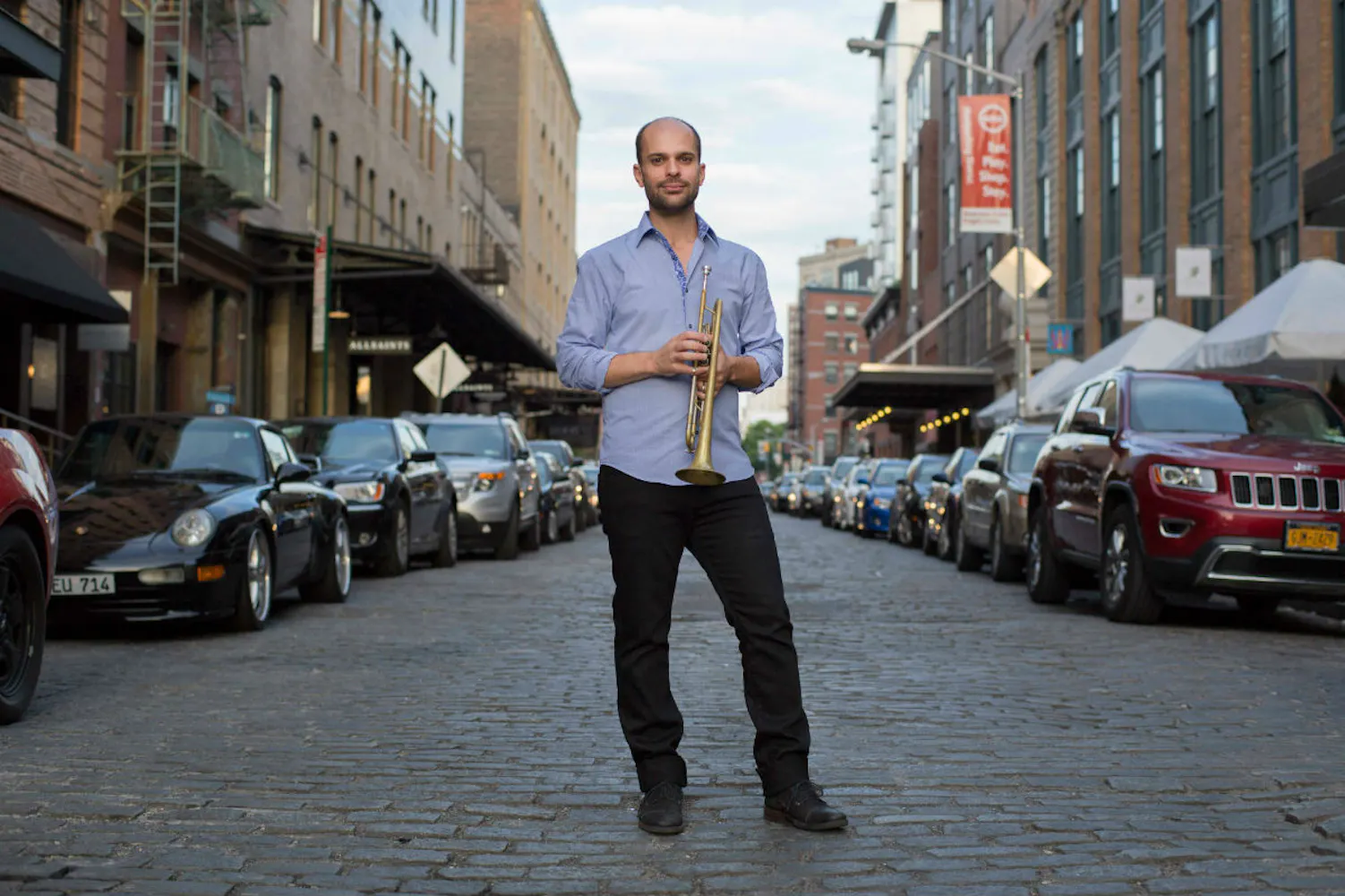 Man standing in middle of city street holding trumpet