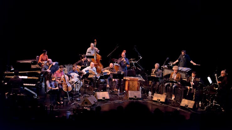 Seventeen-person band performing on stage with a variety of instruments