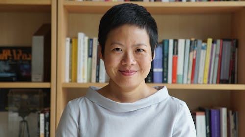 portrait of Anocha Suwichakornpong with bookshelves in the background.