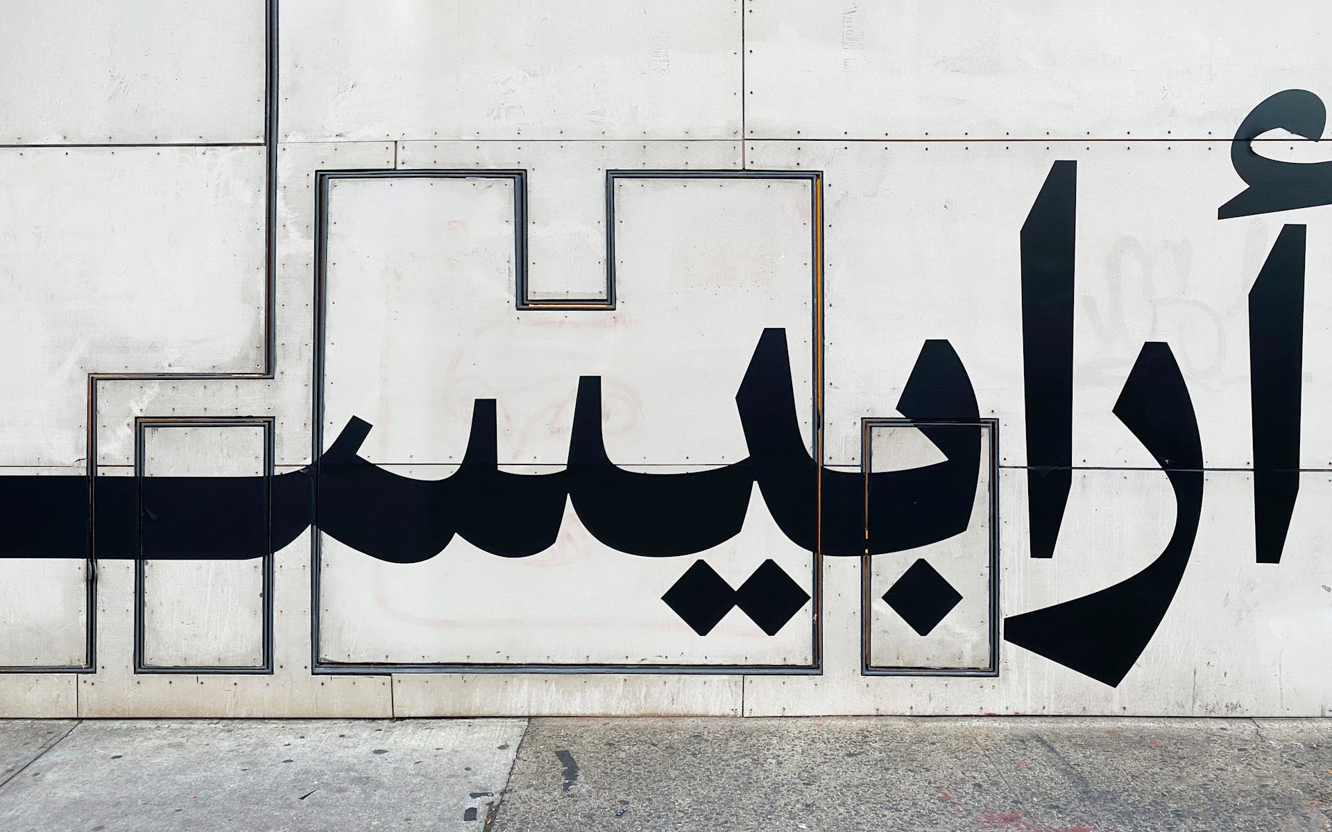 Image of wall with black Arabic typography at a large scale