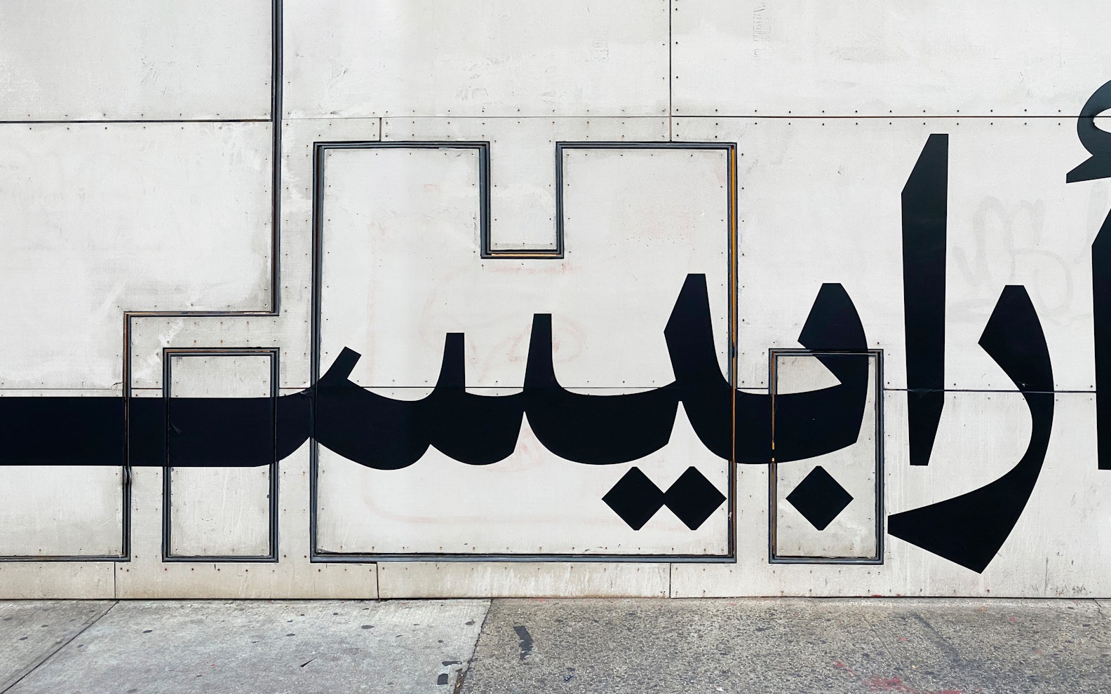 Arabesque — Morcos Key Image of wall with black Arabic typography at a large scale