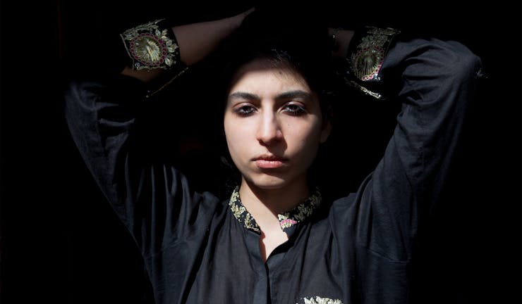 Portrait of woman with hands on her head in black shirt on black background