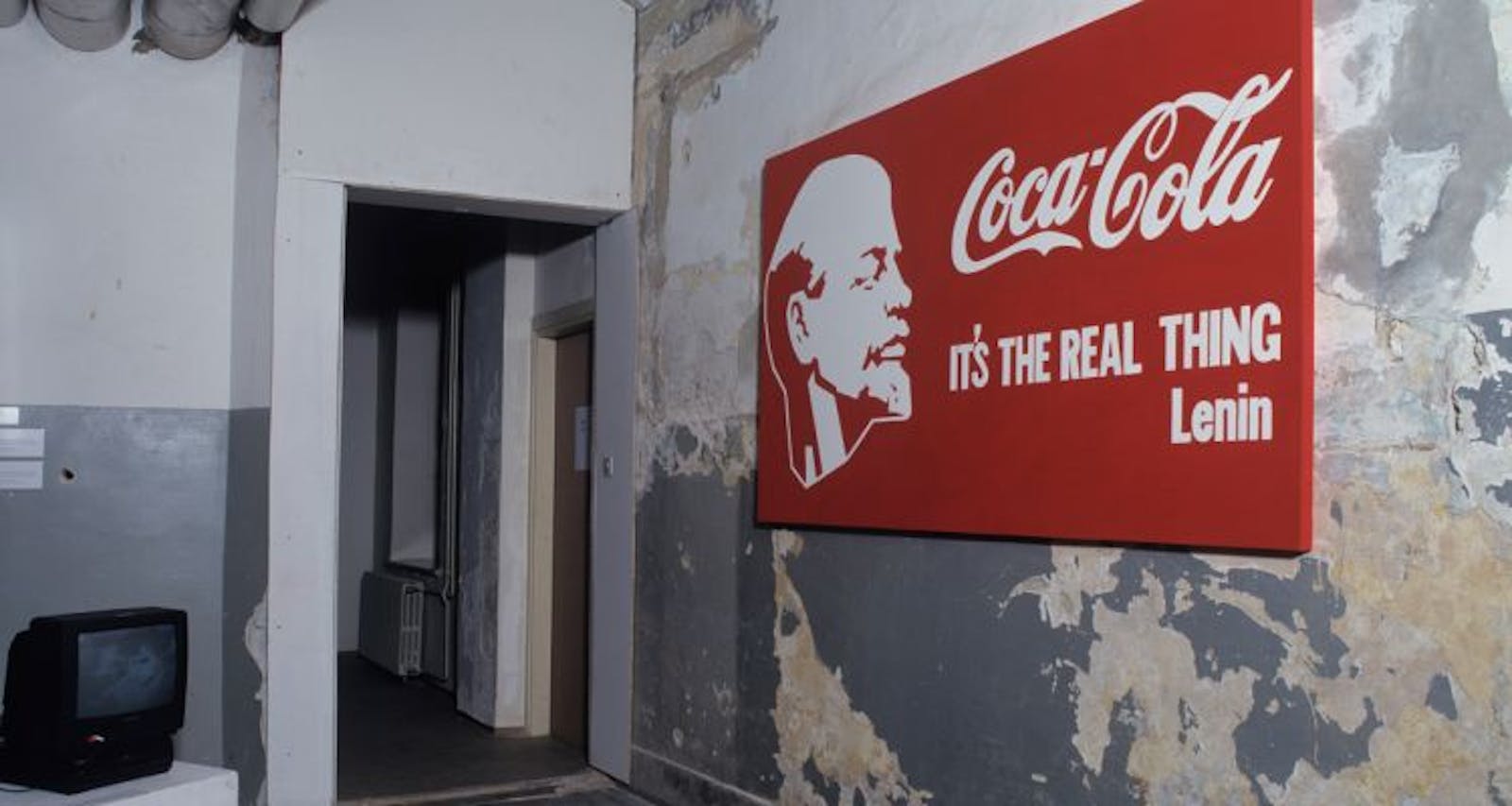 A red Coca-cola sign on a distressed wall.