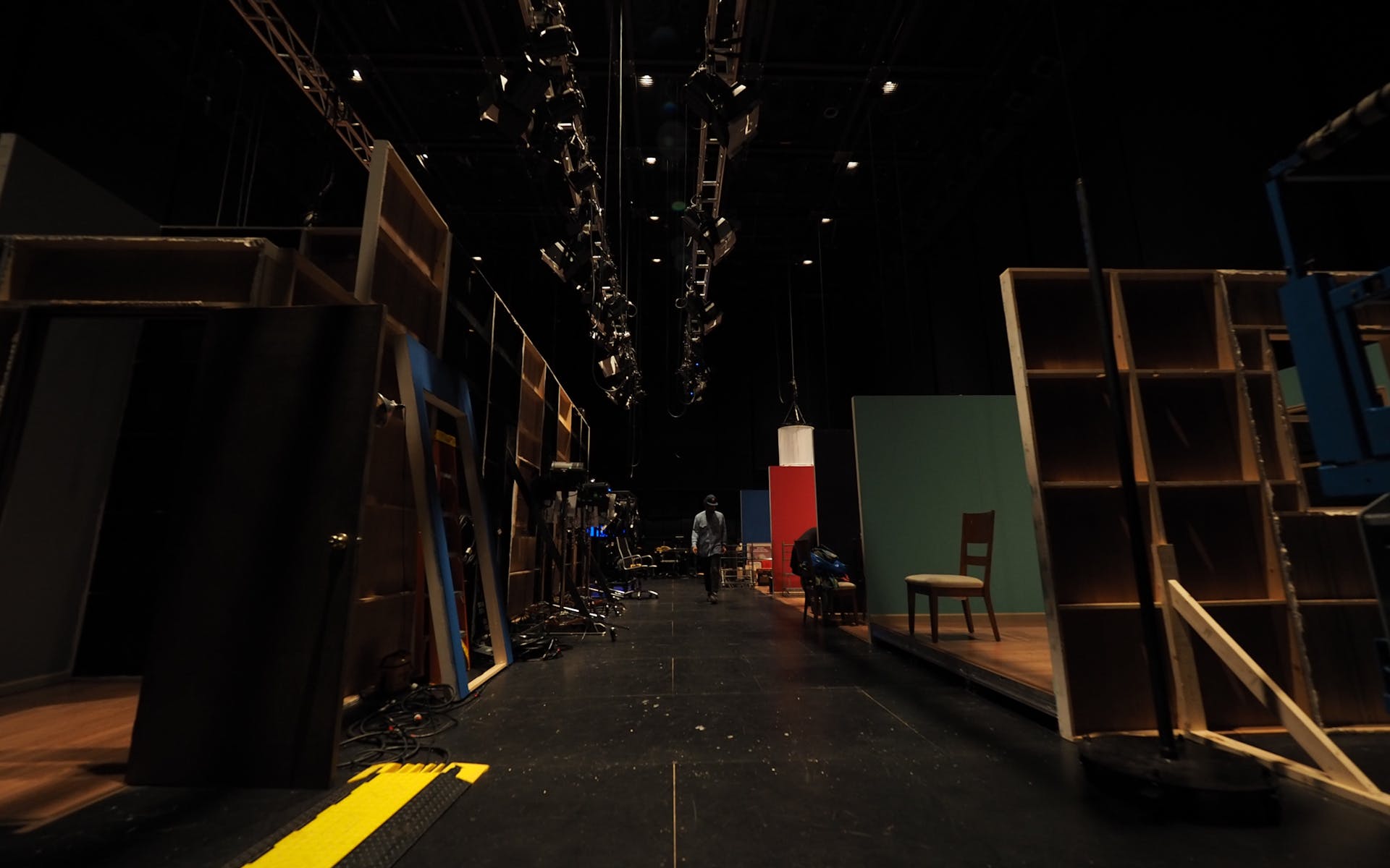 A man walks through the darkened backstage of a theater.