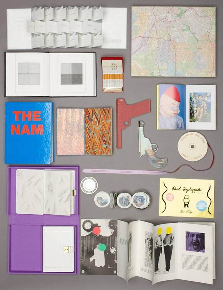 A group of artist's books and spread out over a table.