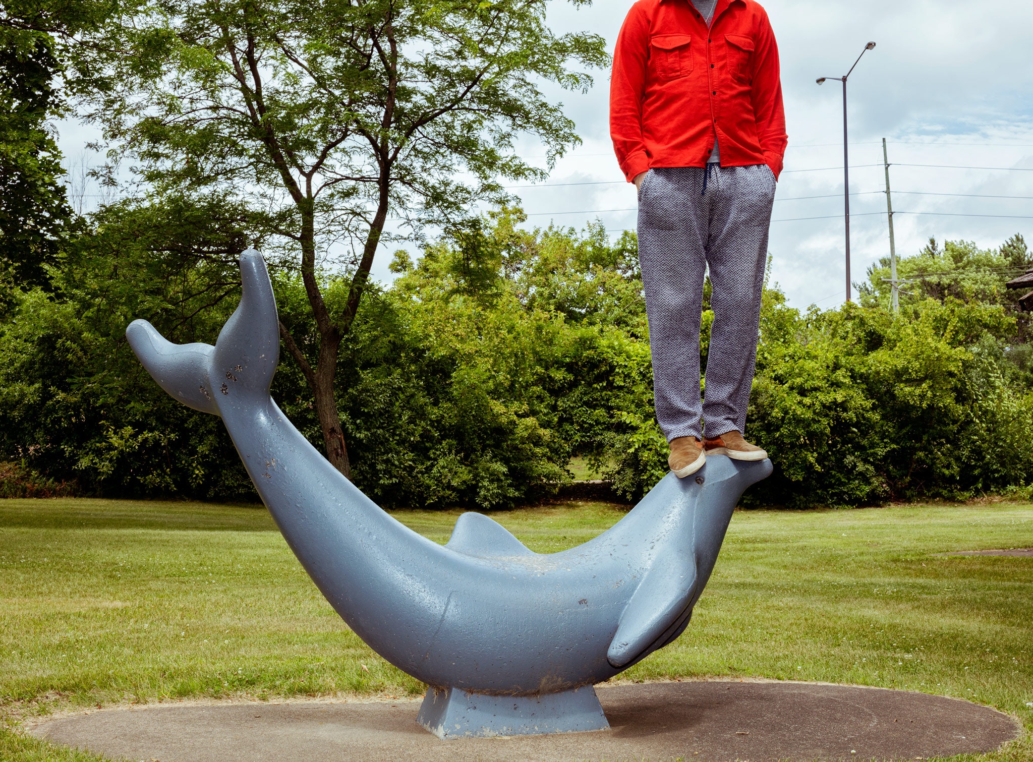 man standing on sculpture of dolphin