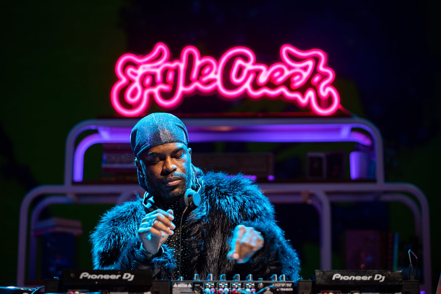 A DJ mixes in front of "Eagle Creek" sign over head.