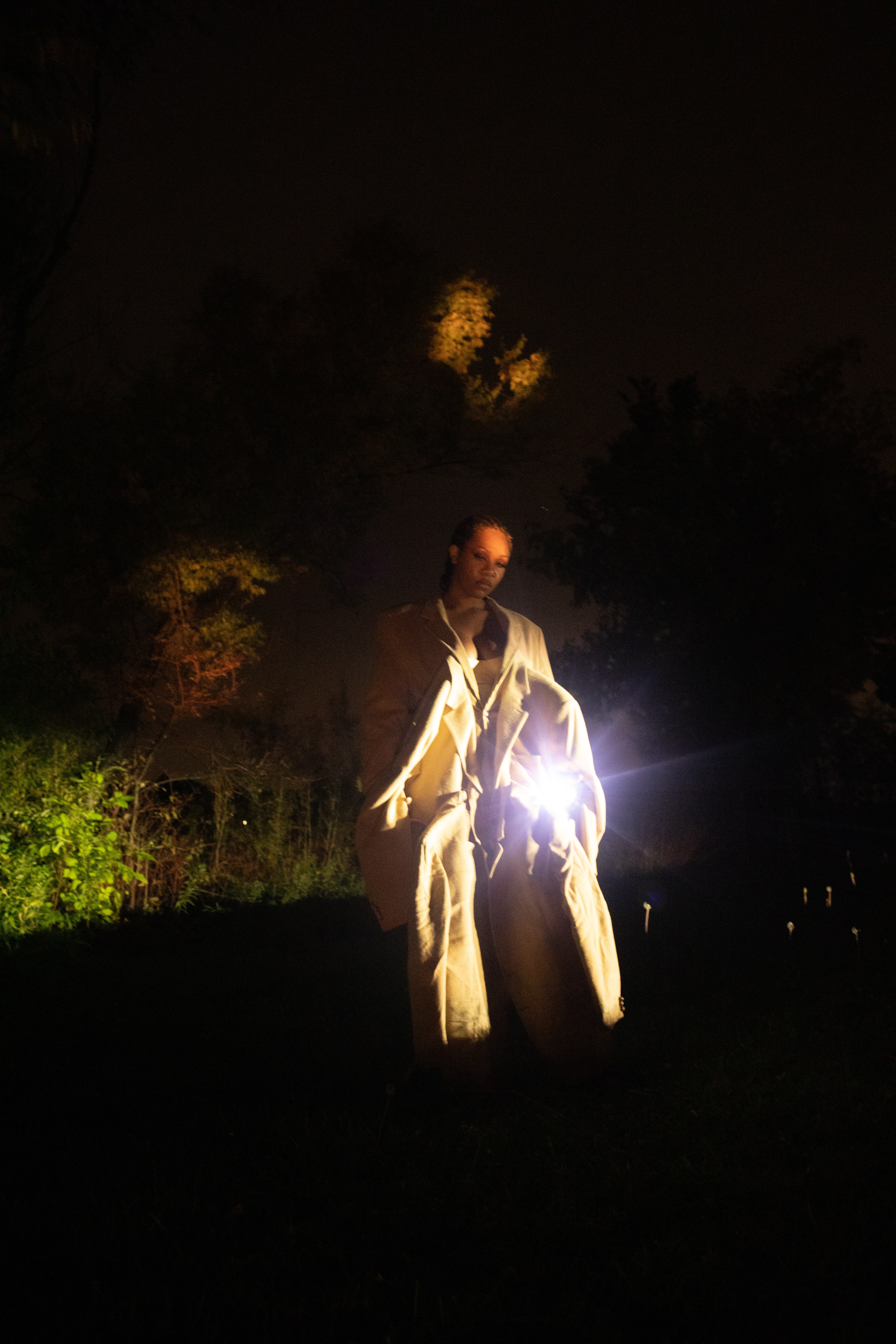 A person stands outside at night holding something glowing.
