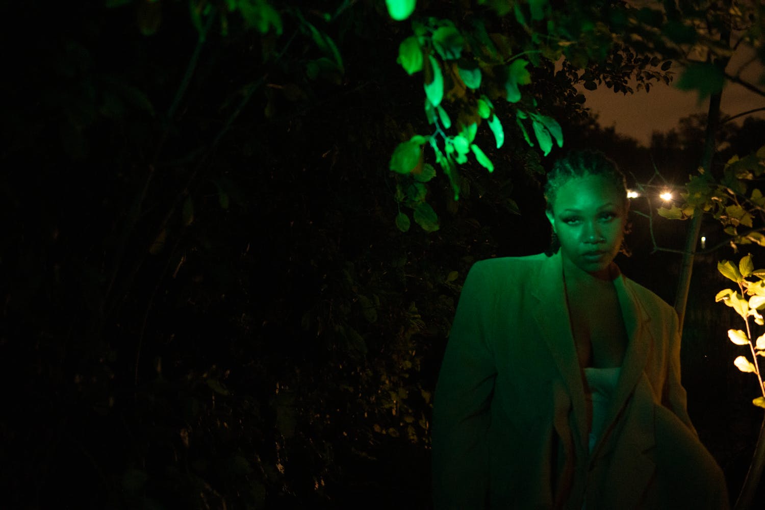 A person looks at the viewer as green light illumates them.