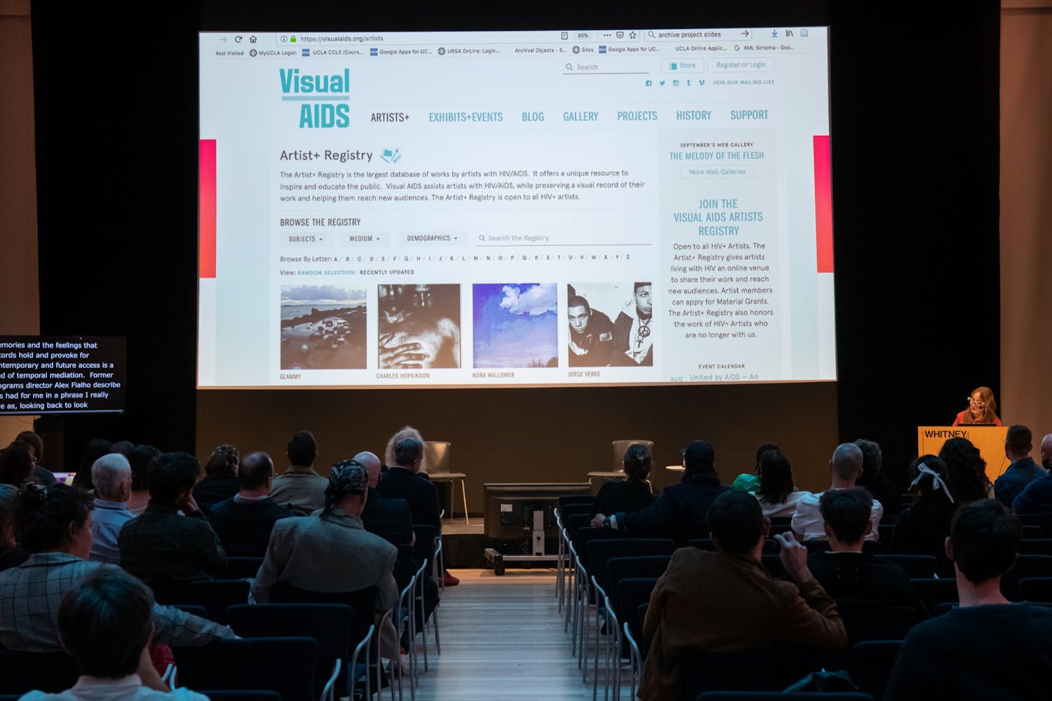 A group of people watch a projected images in a auditorium.
