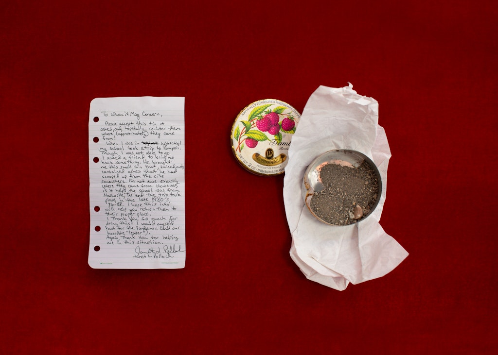 A handwritten note and a floral tin on a red background.