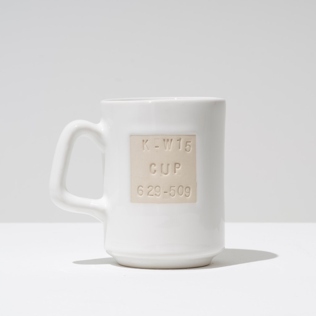 A plain white handled cup stamped with manufacturers' marks.