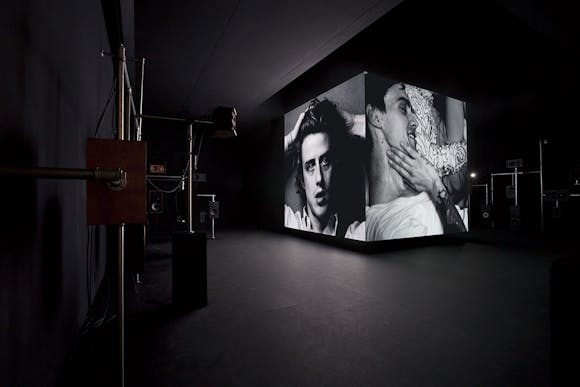 Image of cube structure in gallery with images projected on to the sides
