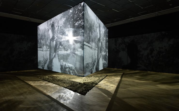 Image of suspended cube within a gallery with images projected on each surface