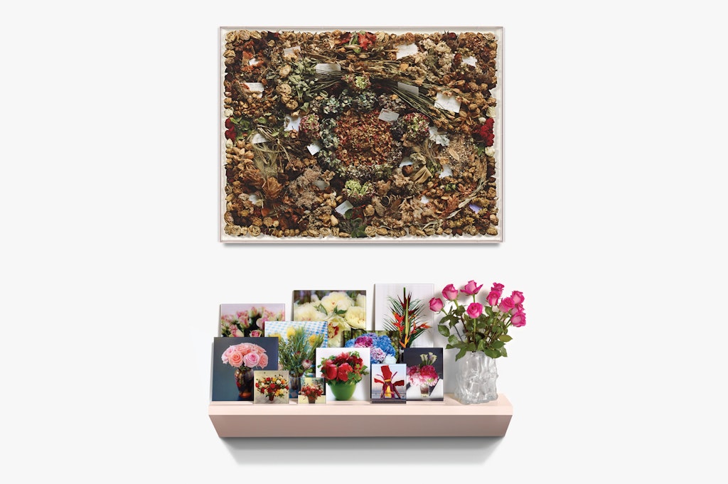 Art with flowers on a wall, and a shelf below with photos of fresh flowers and a vase of pink roses