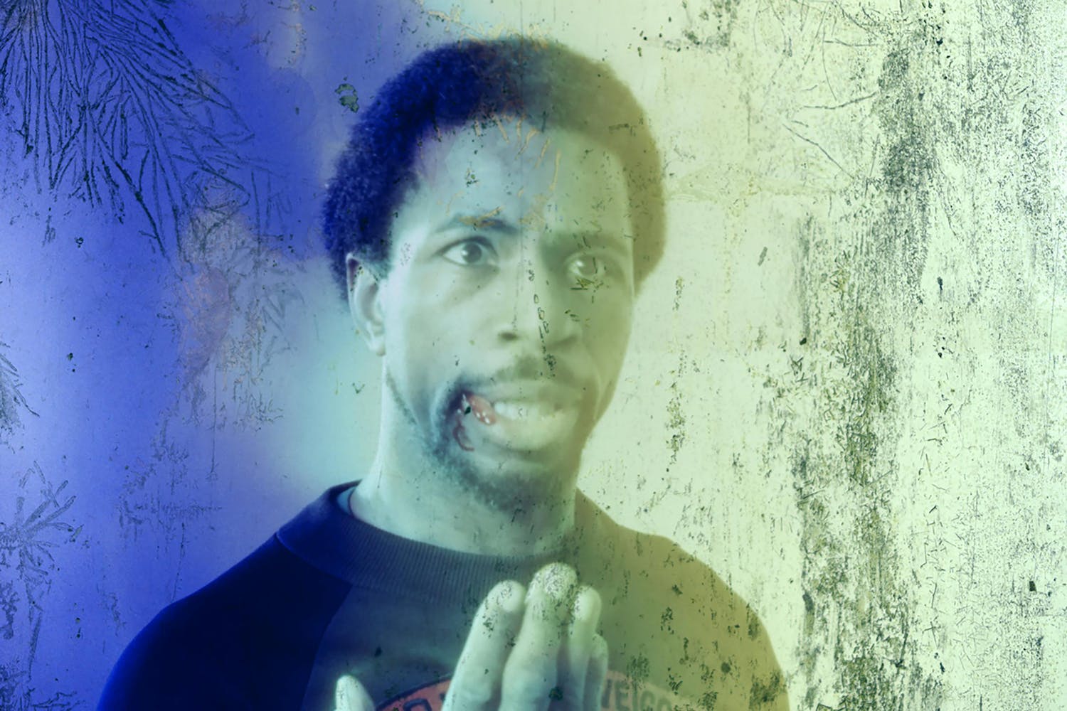 A weathered film still of a black man speaking.