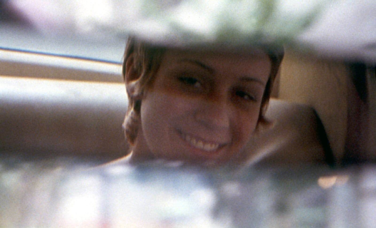 Teenage girl smiling seen through the rearview mirror.