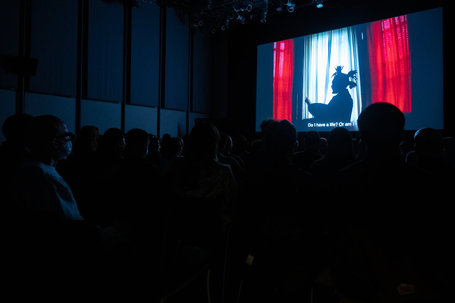A group of silhouetted people watch a projected images in a auditorium.