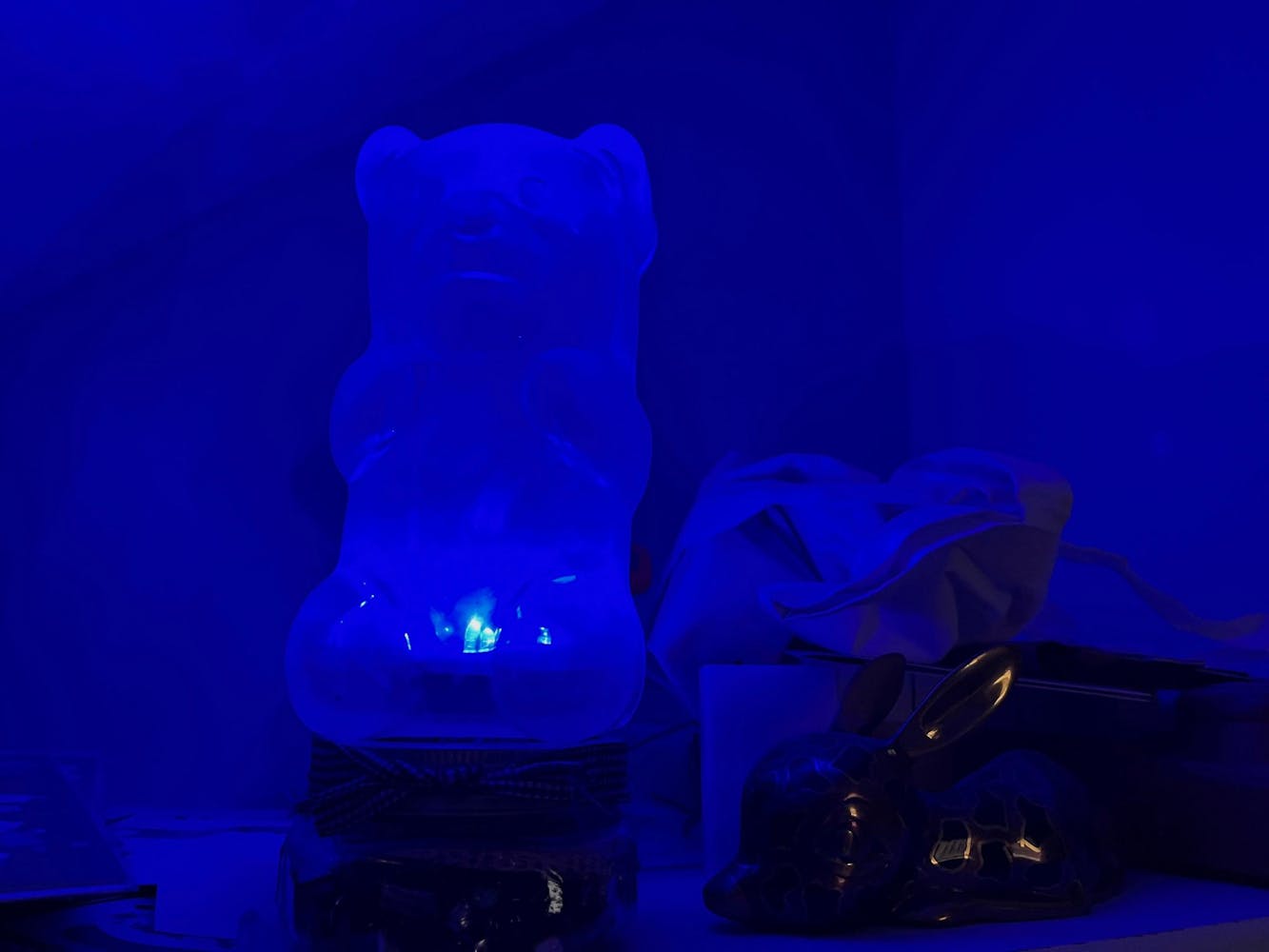 a lit blue gummy bear lamp next to a bunny statue