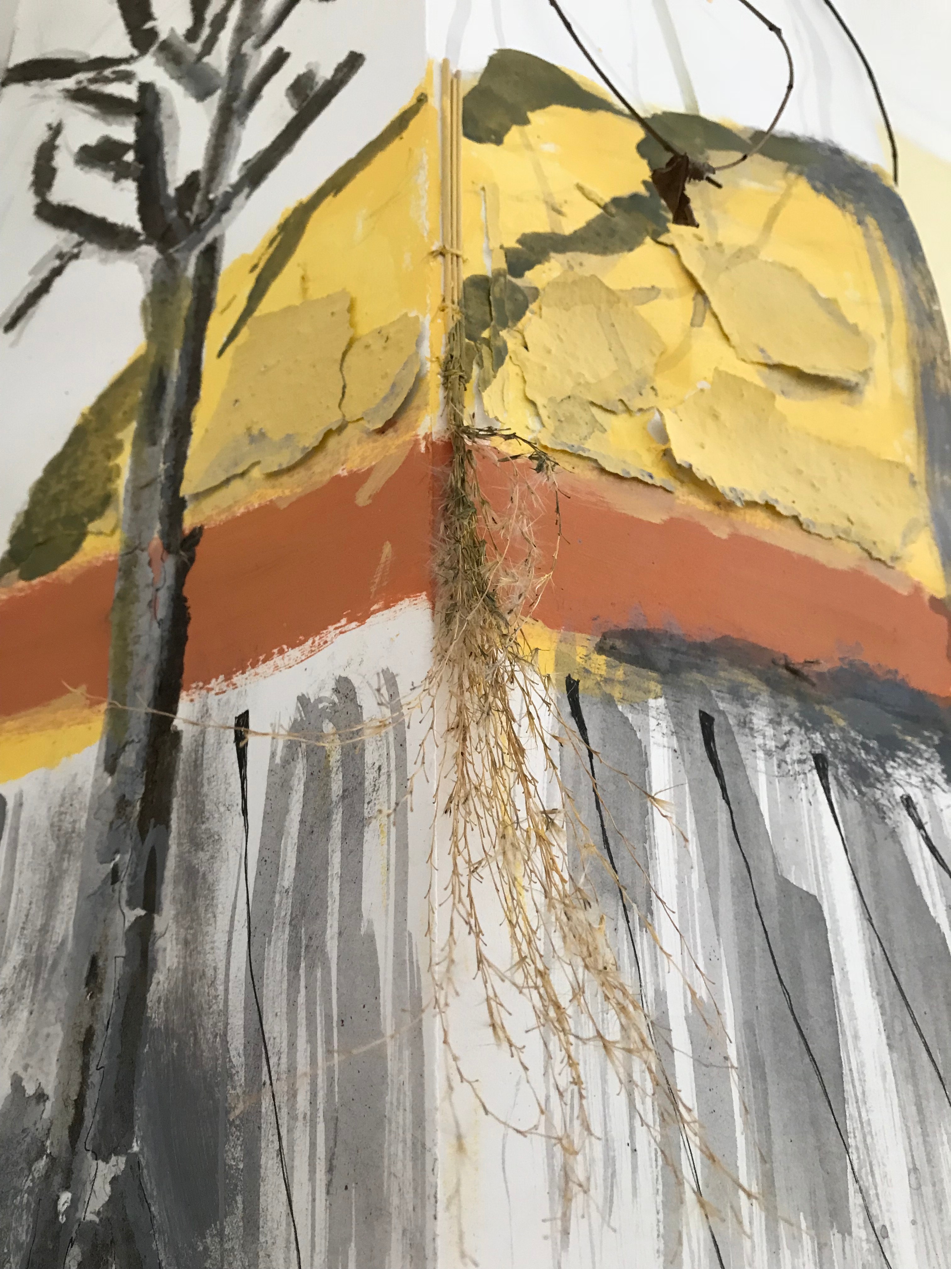 Black/grey vertical strokes of paint make up the base, and a black tree is on the left. There is an orange stripe in the middle and yellow above it with some patches on it painted the same color. A dried plant hangs in the middle