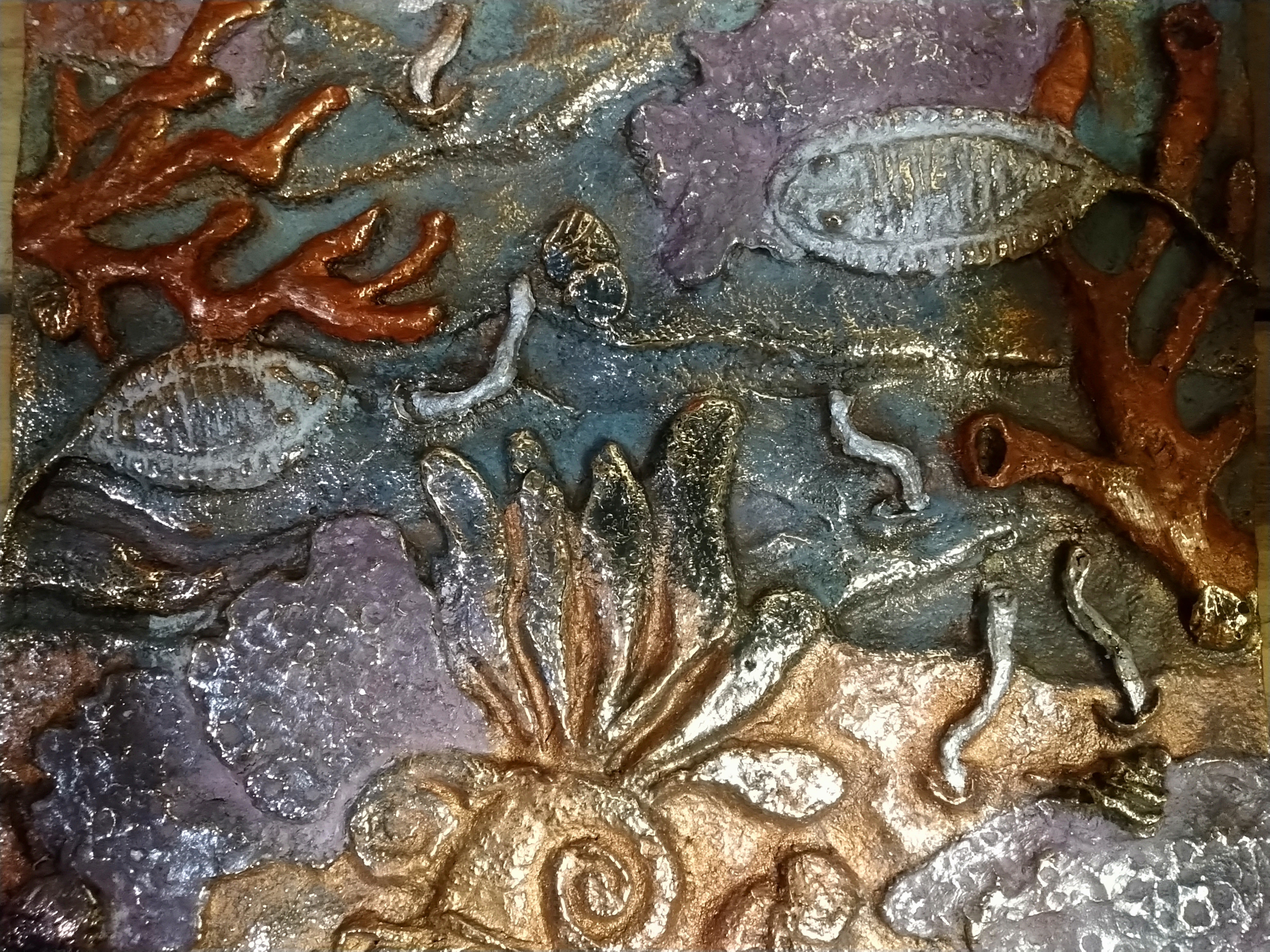 A textured surface which has coral, fish or fossils and an underwater feel. The paint has dark colors and a gold metallic sheen