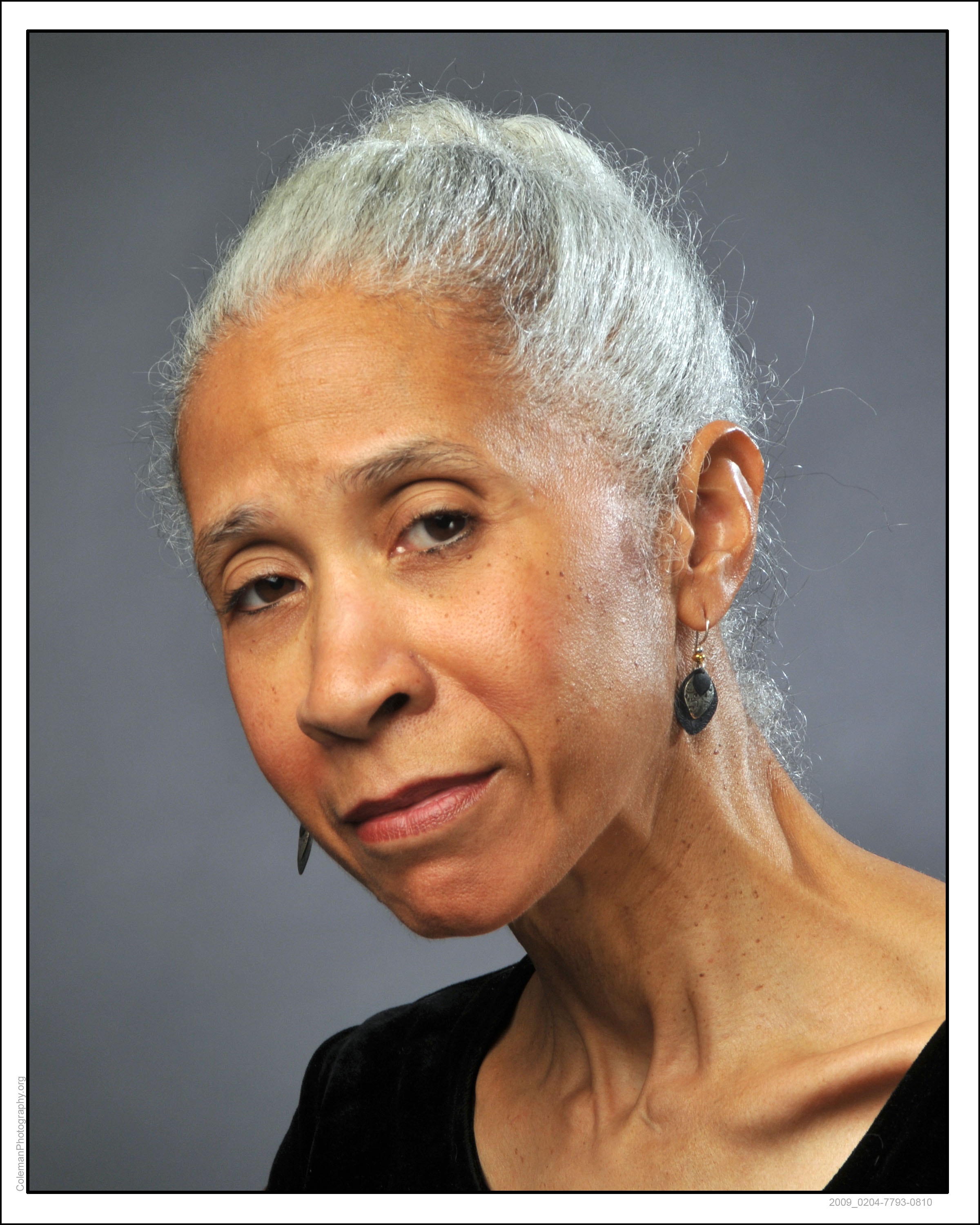 A woman with dark skin looks at the viewer.