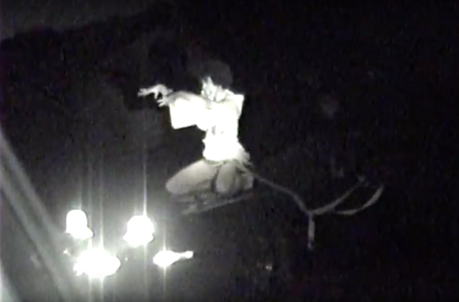 A crouched man holds his hands up.