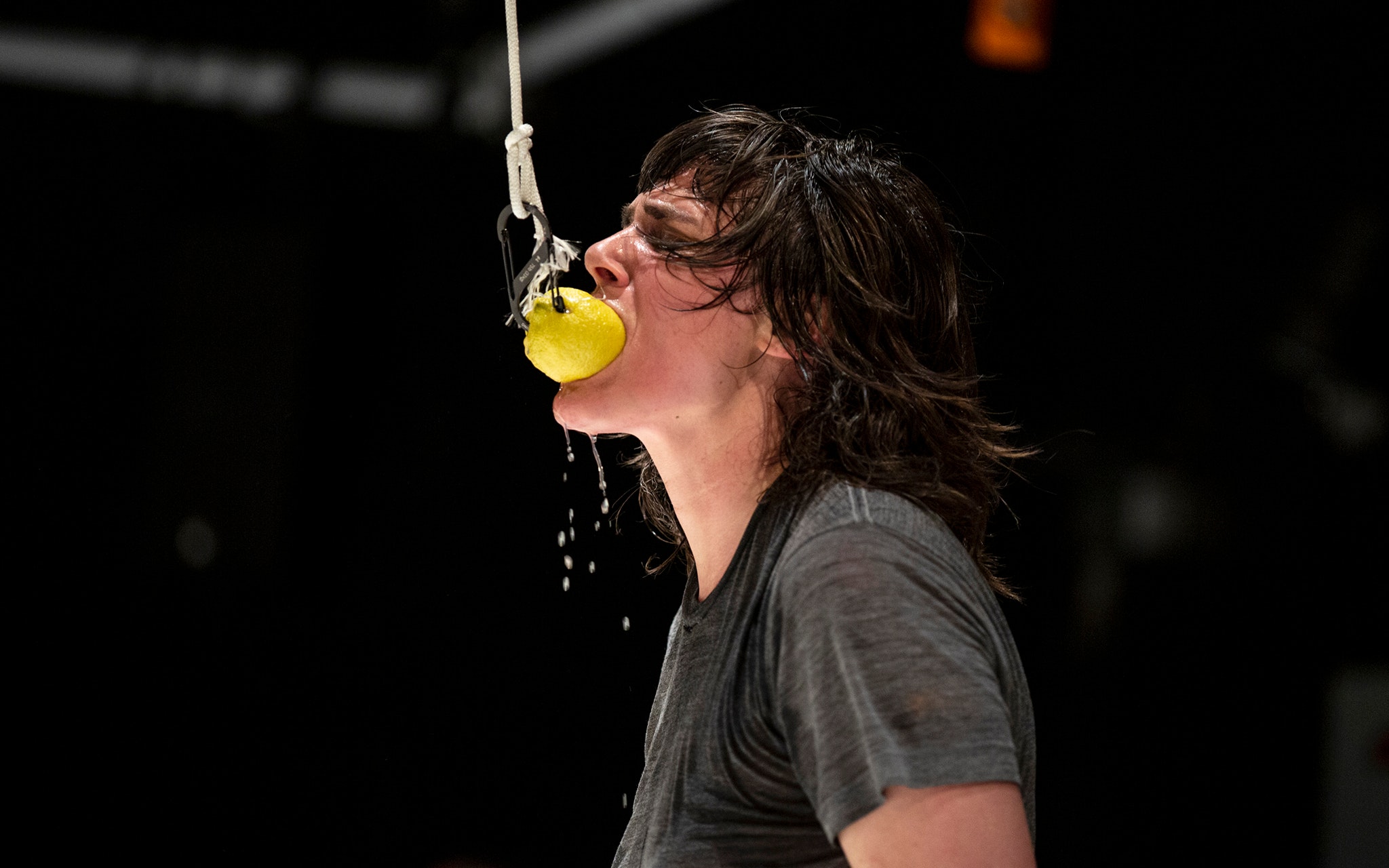 Faye Driscoll biting a lemon on a string.