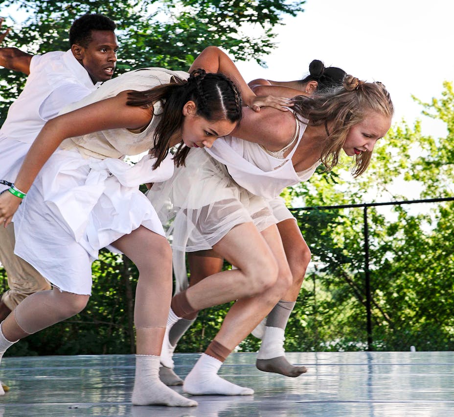 Two woman in white dresses and man in white crouched to run.