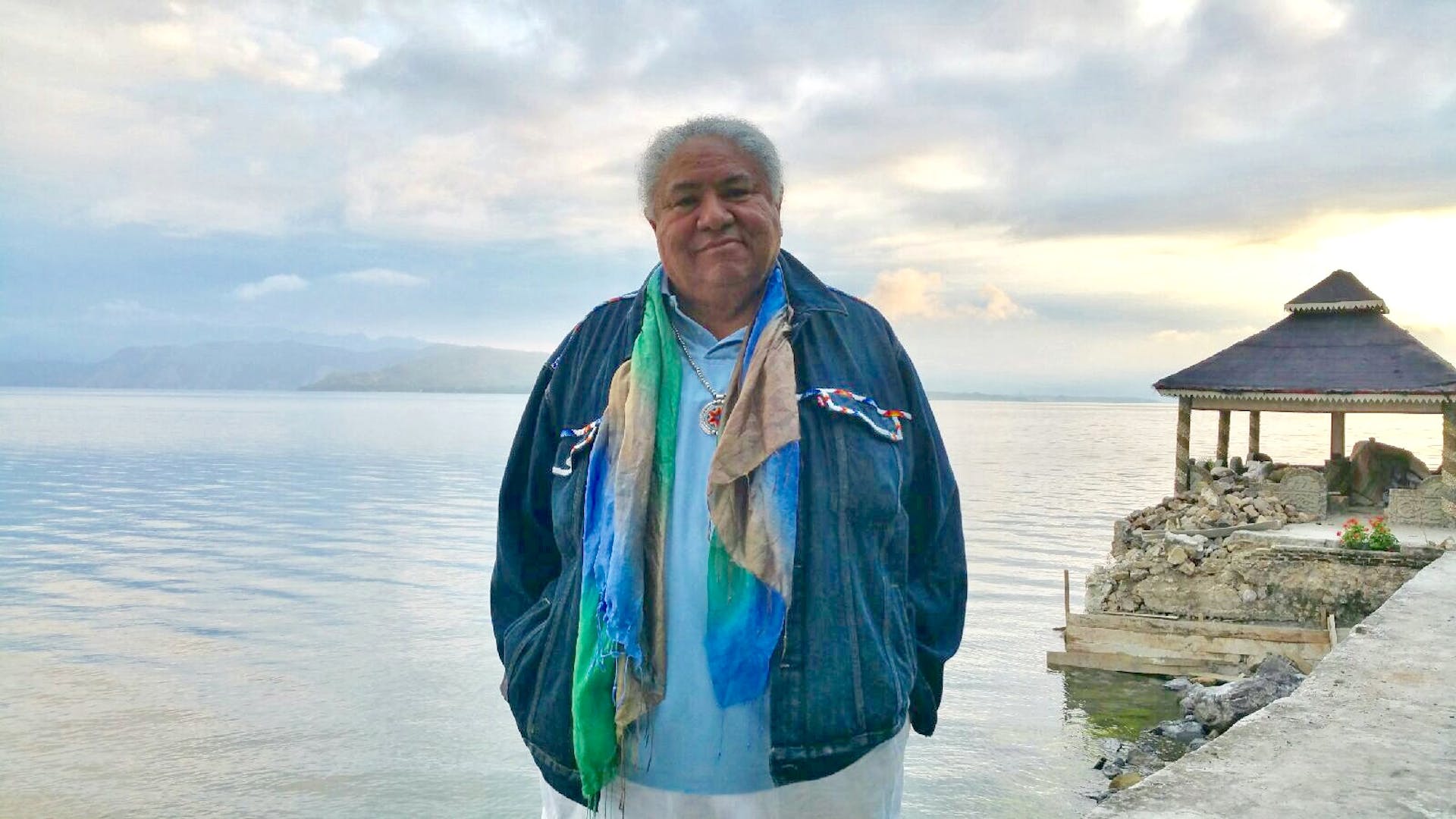 Native man standing in front of a large body of water.