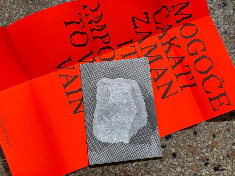 Small black and white image of a rock is laid ontop of a poster.