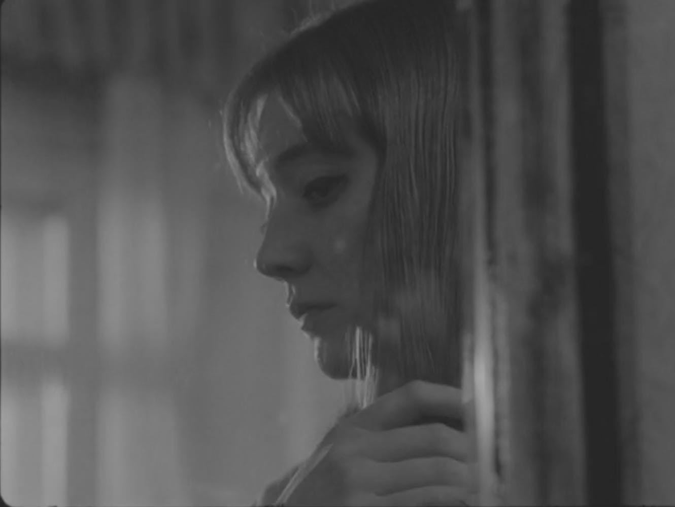 A woman with long hair looks at herslef in a mirror.